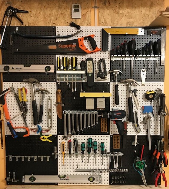 Väggmonterad verktygstavla fullt utrustad med olika handverktyg, inklusive hammare, tangenter och skruvmejslar.