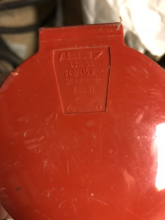 Närbild av ett rött 63A skarvuttag märkt med "ABL" samt information om spänning och konfiguration.