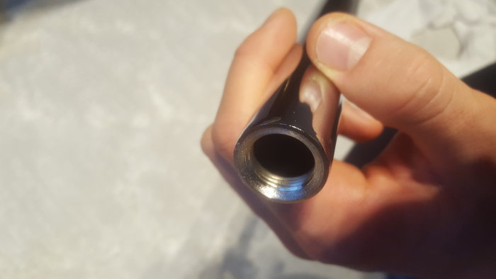 Närbild på en förkromad rördel med invändig gänga hållen av en person.
