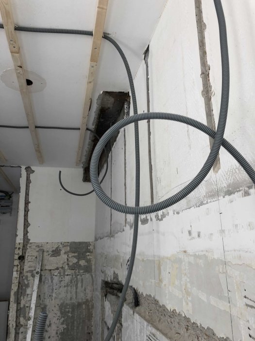 Renoveringsarbete med synliga elinstallationer och flexibla rör mot avskalade väggar och tak.