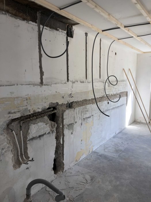 Renoveringsrum med öppna vägguttag och kablar, utmejslade spår i väggen och golv.