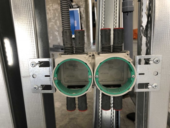 Installation av dubbla elektriska dosor med anslutna kabelskyddsrör i en metallstomme.