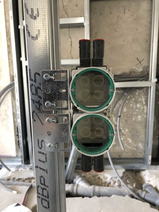 Installation av väggmonterade eldosa på metallställning med rör och kablar i bakgrunden.