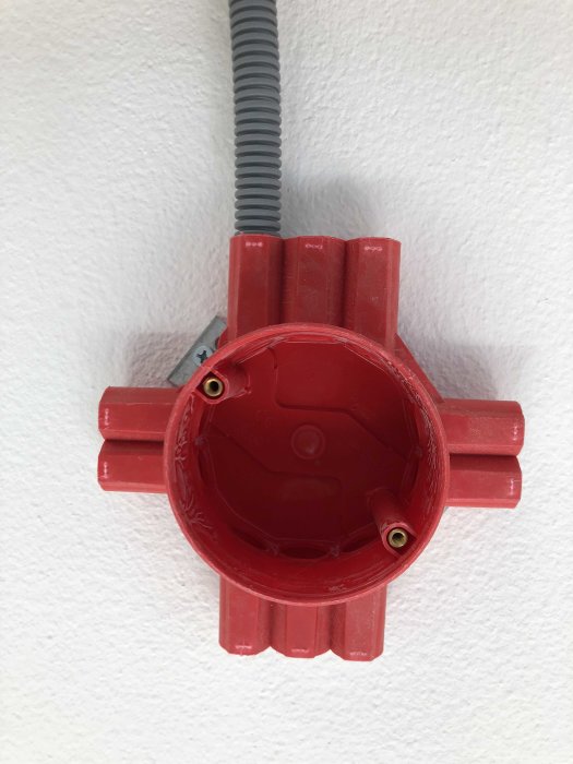 Röd eldosa på vägg med ansluten grå kabelskyddsrör.