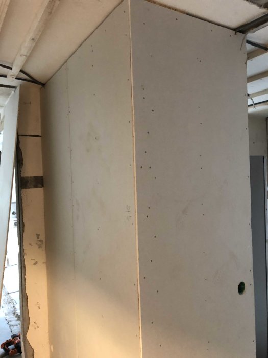 En oavslutad gipsskivvägg i ett renoveringsprojekt med synliga skruvar och ojämn kant.