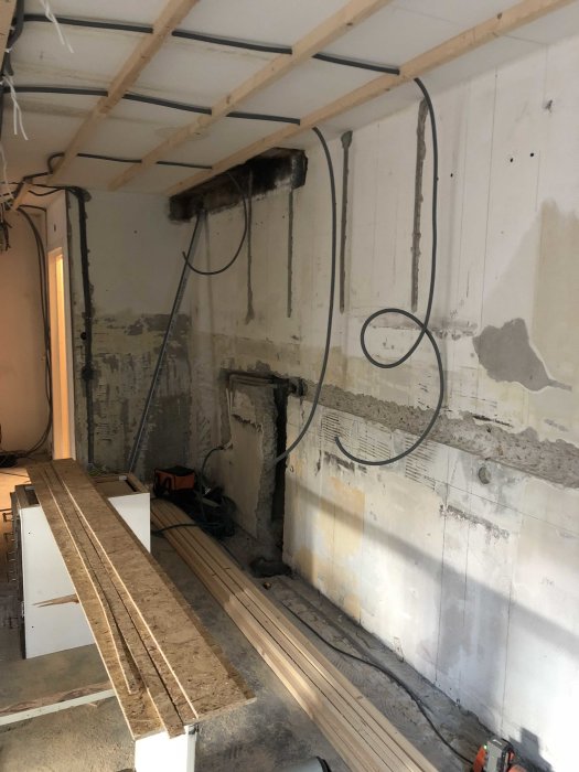 Renoveringsarbete i progress, oisolerade väggar och trävirke på golvet.