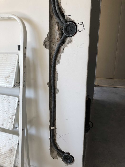 Elledningar och vägguttag på ett ej färdigställt betongvägg vid en renovering.