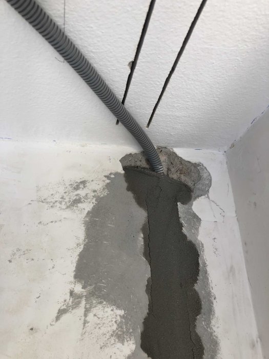 Elrör och elledningar genom en vägg med pågående spackling och reparation av en spricka.