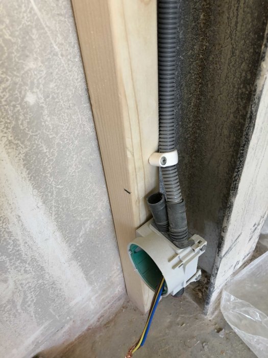 Eluttag under installation med kabel och flexibla rör nära en vägg och en träregel.