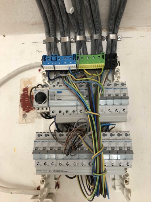 Elcentral med flera grupper av säkringar och kablar i olika färger organiserade på en vägg.