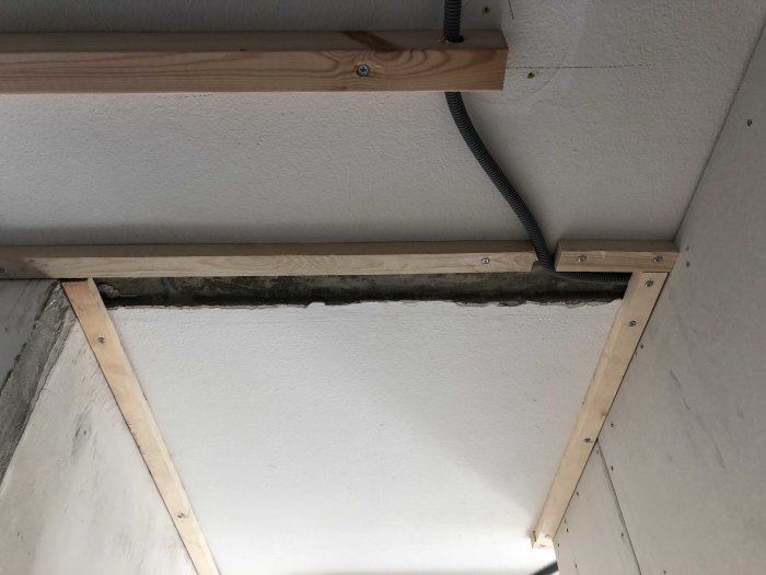 Tak med synlig träregel och elkabel längs en obehandlad betongkant.