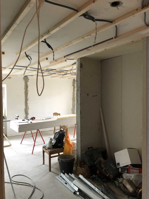 Renoveringsrum med osanerade kablar, gipsskivor och byggmaterial.