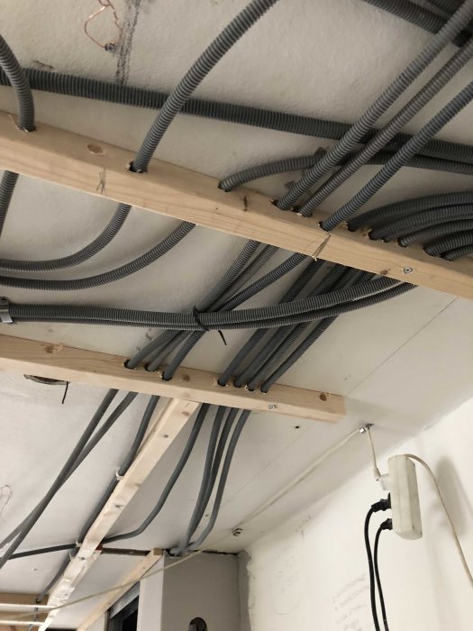 Installation av flexibla elrör fastsatta på träreglar under ett betongtak i ett renoveringsprojekt.