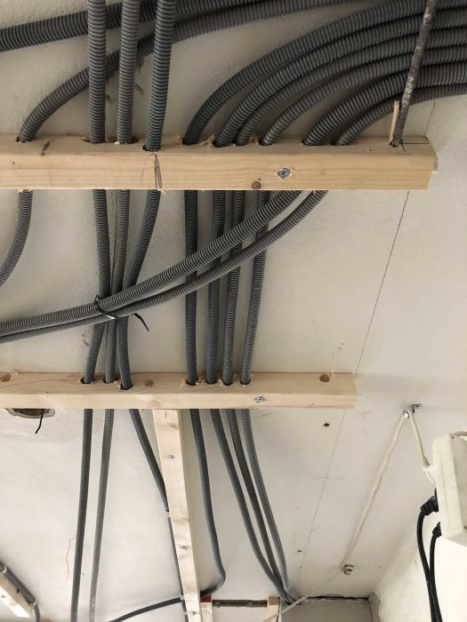 Elektriska installationer med flexibla rör ordnade på träreglar under ett tak.
