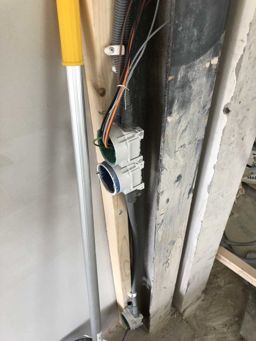 Eluttag monterat på regel med elkablar i väggen under renovering.