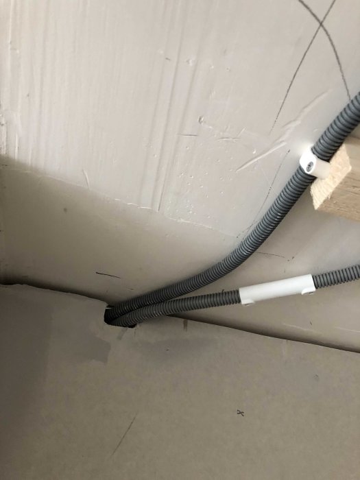Elledningar dragna längs en vägg och fastsatta med kabellist i ett hörn.