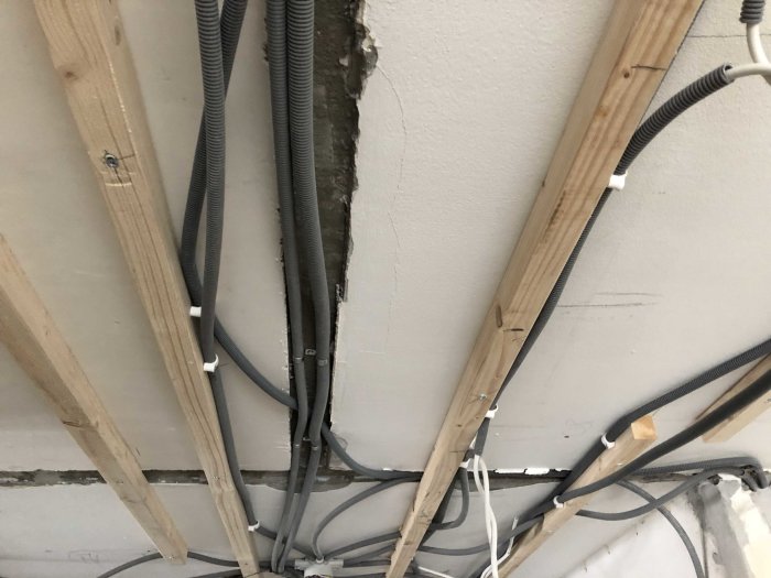 Elinstallation i pågående renovering med synliga kablar och träreglar under betongtak.