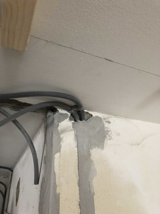 Elrör ledande ner i ett otillräckligt fäst vägggenomföring med spackel arbeten pågår.