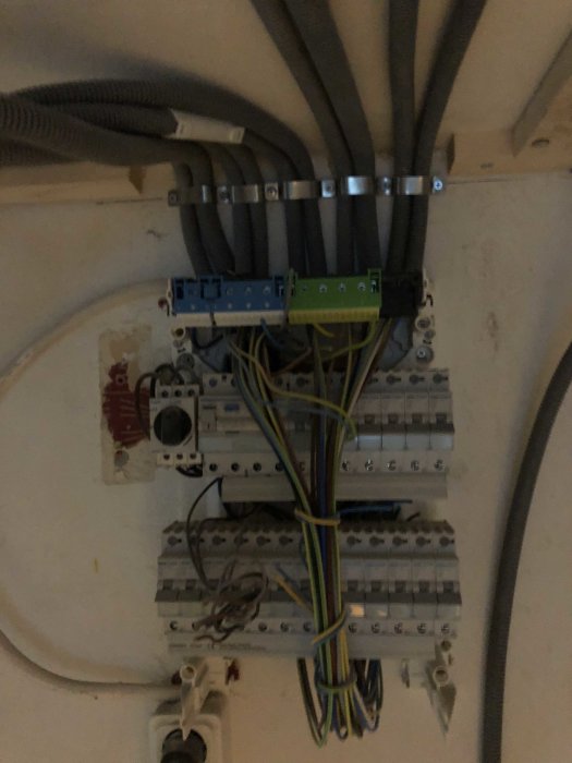 Elcentral med kablar, säkringsdosor och anslutningsklämmor i oordning och öppen installation.