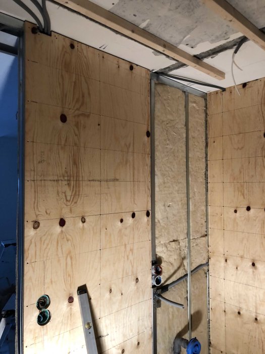 Vägg under konstruktion med OSB-skivor och isolering synlig, elinstallationer pågår.