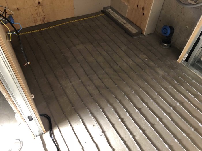 Golvvärmeinstallation med synliga värmeslingor på betonggolv i pågående byggprojekt.