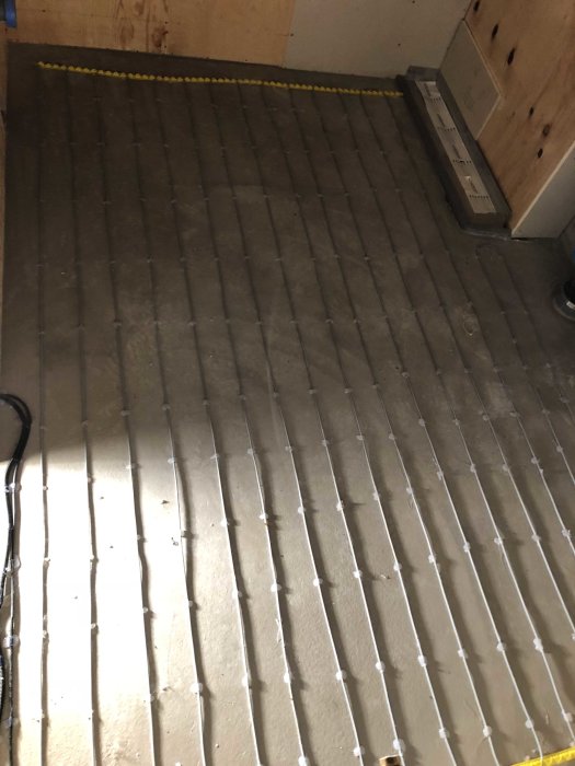 Golvvärmeinstallation i pågående arbete med synliga värmeslingor och klammer på betonggolv.