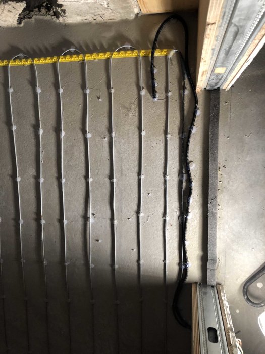 Elledningar som fästs längs en vägg med vita klammer och måttband längst upp.