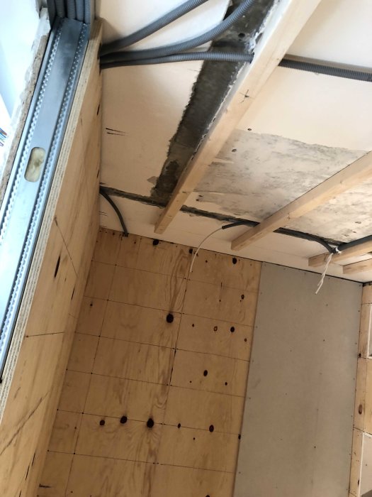 Upprivet golv och tak som visar rördragning och träbjälkar för renovering.