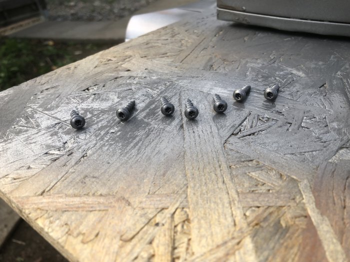 Skruvar i linje på träyta förberedda för användning i byggprojekt, markerade med laser.