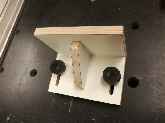 Trähållare med två svarta knoppar på verktygsbord, tänkt för förnödenheter under hyvling.