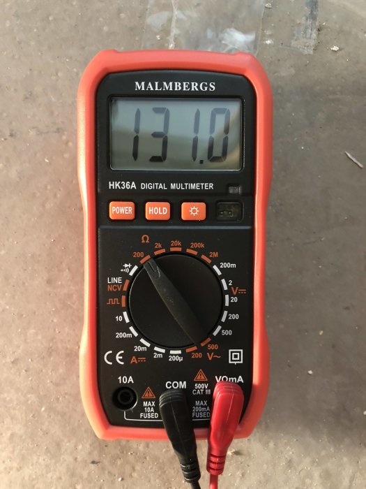 Digital multimeter som visar 131,00 ohm på displayen mot en suddig bakgrund.