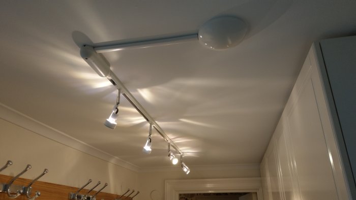 Takmonterad skena med riktbara spotlights och en gömd lamppropp i ett kök.