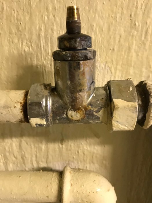 Gammal termostat med läckage vid anslutningen till rör, synliga droppar och korrosion.