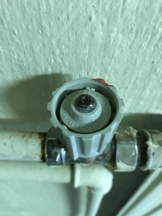 Termostat med avtaget vred som visar en mutter och läckage vid anslutningen till radiatorröret.