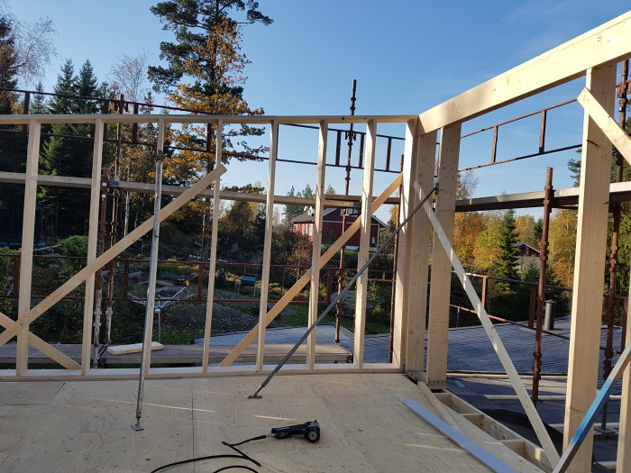 Konstruktion av en andra våning med upplyfta takreglar, utplacerade fönster och verktyg på golvet.