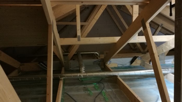 Ventilationsrör installerade i ett husvindsutrymme med synliga träbjälkar.