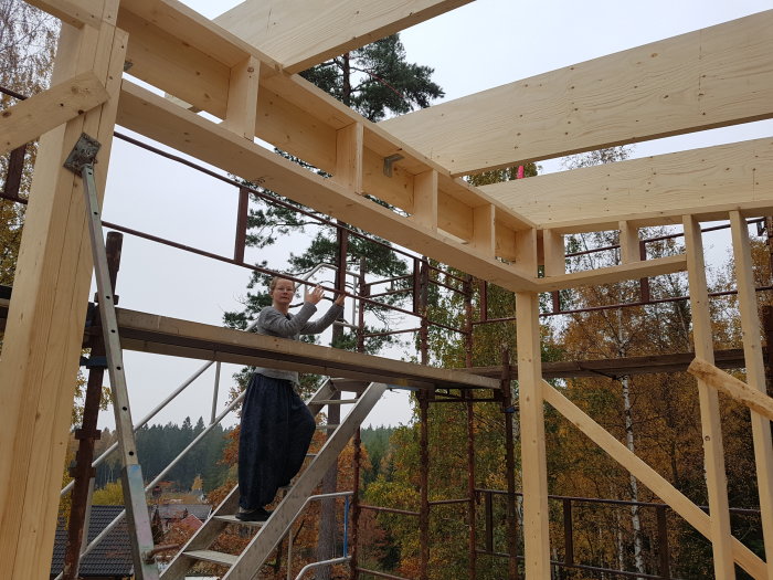 Trästomme till en andra våning under uppbyggnad med takreglar och en person som arbetar.