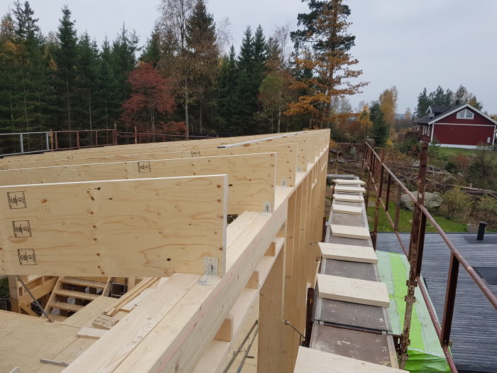 Nybyggda väggar med träreglar och Kerto balkar på andra våningen, ställningsgång bredvid.