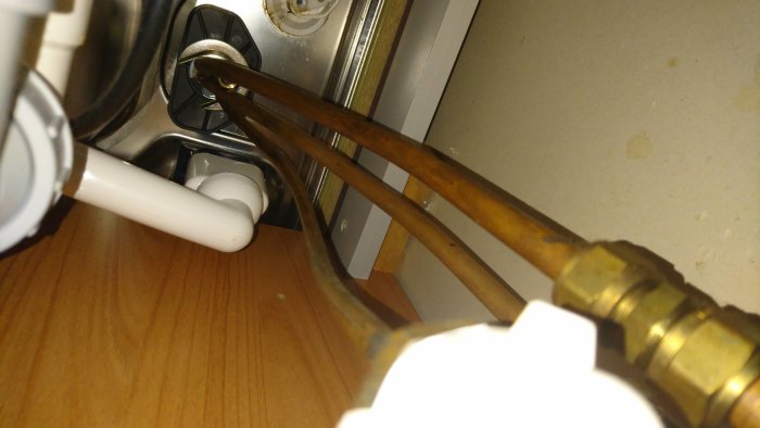 Rörkopplingar under diskbänk med öppet vred till diskmaskin, kopplat till kallvatten.