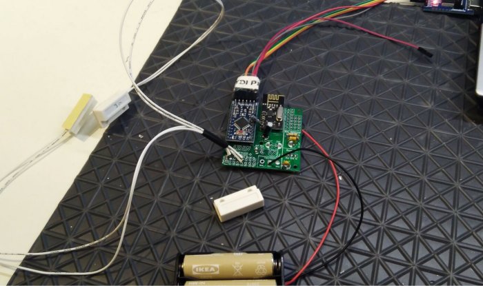 Elektronikkomponenter och batterier på ett bord för att bygga en sensor som övervakar en kattlucka.