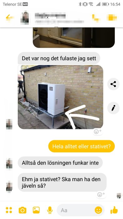 Installation av värmepump på ett metallstativ bredvid en husvägg, med diskussion om utseende och funktion i ett textmeddelandefönster.