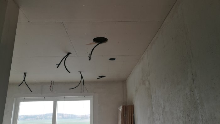 Installation av takhögtalare med synliga ledningar i ett rum under konstruktion.