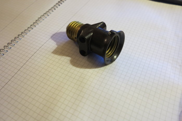 En svart och gul gammaldags keramiksäkring på ett rutat papper.