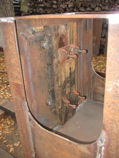 Svetsad metallstomme med rost och fastrostate delar av ett hjulsystem, i en byggnadsprojektmiljö.