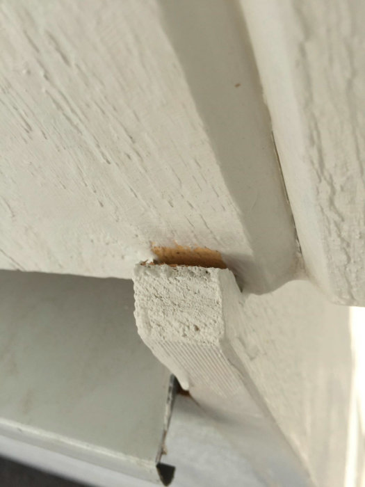 Närbild på glipa överst på en vitmålad träkonstruktion som behöver tätas för att förhindra regninträngning.
