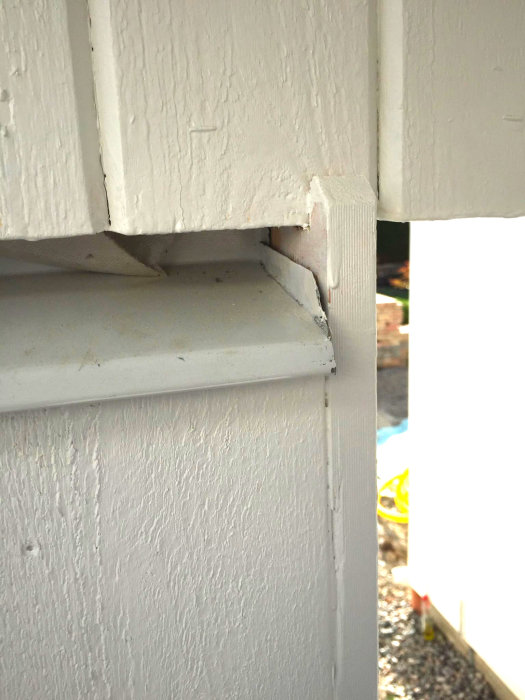 Vit målad träkonstruktion med synlig springa där det kan läcka in regn.