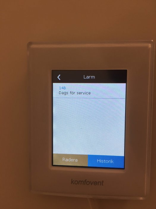 Display som visar ett larmmeddelande "Dags för service. 14B" på en väggmonterad kontrollenhet.