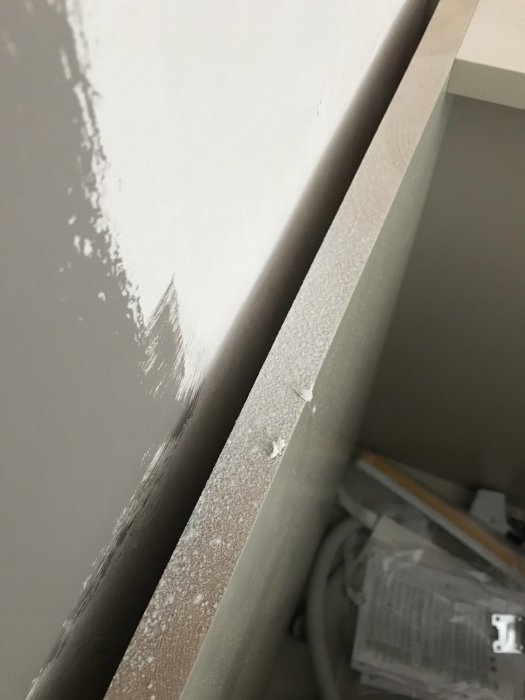Köksstomme med damm i glipan mot väggen, oskyddad karm vid skjutparti, öppen golvsockel.