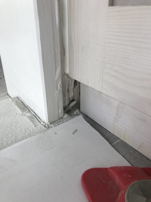 Oskyddat hörn med synlig skada och damm mellan köksskåp och vägg under renovering.