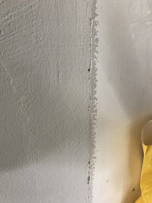 Närbild av ett dåligt spacklat hörn mellan vägg och köksstomme med synlig glipa och damm.